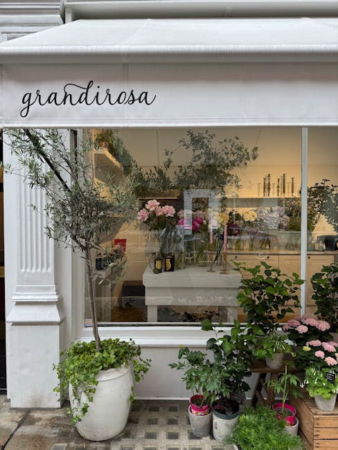 A view of the exterior of Grandiroza, a flower shop on Charlotte Street Fitzrovia, with a large white awning displaying the shop's name in elegant black script. In front of the shop, there are several